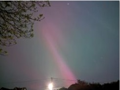 The picture of aurora shows a vertical beam stretching diagonally from the overhead aurora corona down to the horizon behind a house in Telford Shropshire UK